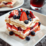 Slice of Strawberry Tiramisu recipe topped with fresh strawberries and blueberries