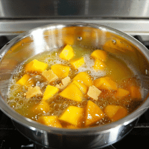 Chopped mangoes boiling in a saucepan with water