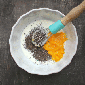 Chia seeds and mango pulp in a mixing bowl with whisk