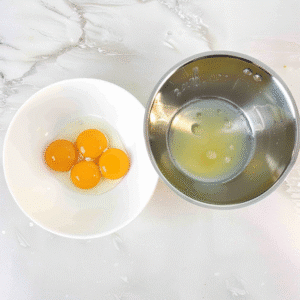 Egg yolks and egg whites separated in bowls for cloud cake preparation