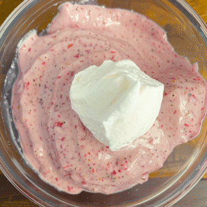 Strawberry ice cream base with whipped cream in bowl