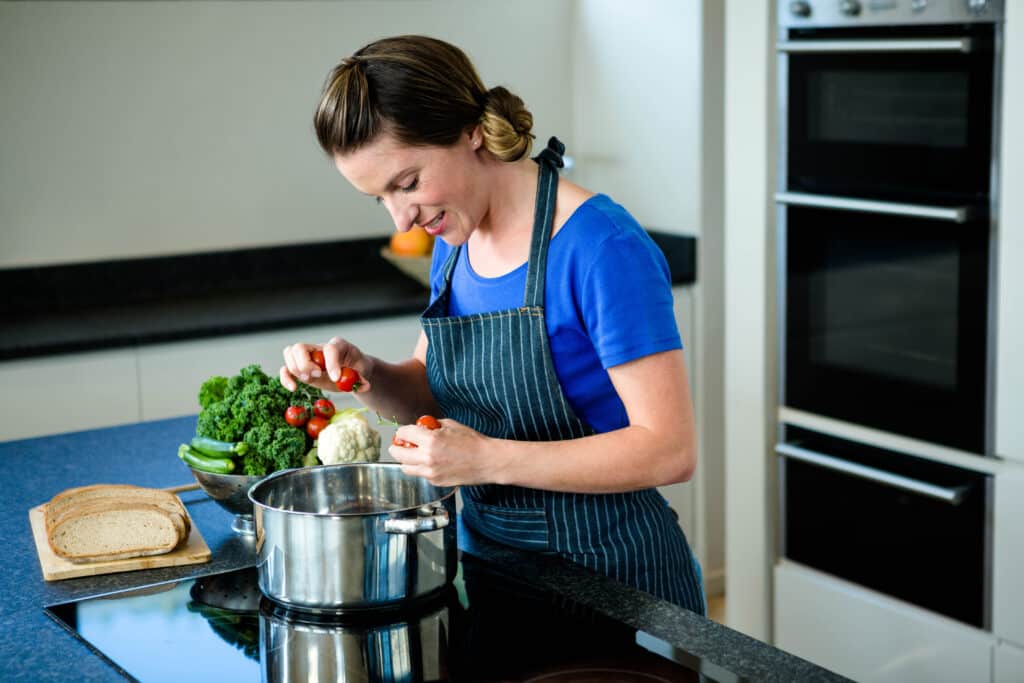 Authors 2 smiling woman cooking vegtables saucepan stove top 1